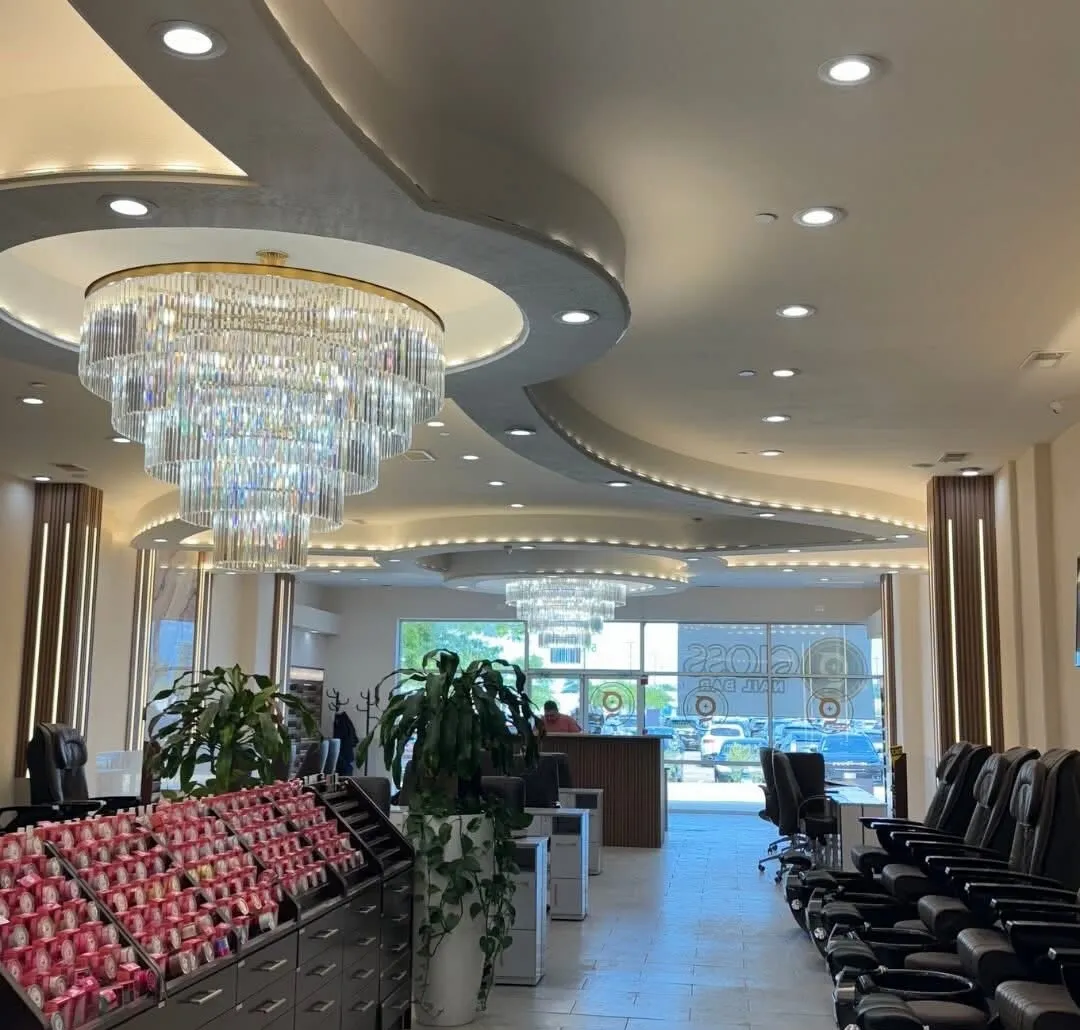 Grand main floor at Gloss Nail Bar Niles — cascading crystal chandeliers above the polish wall, spa pedicure row and reception