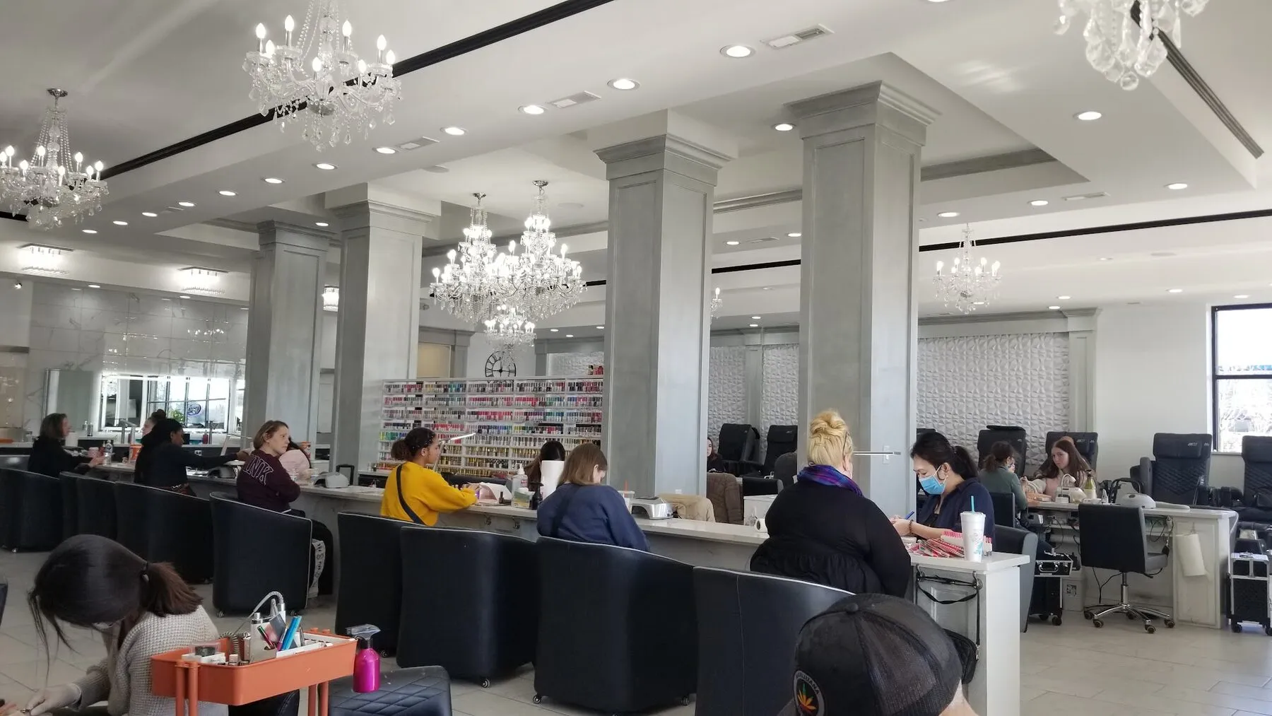 Rows of marble manicure stations beneath crystal chandeliers, busy with guests