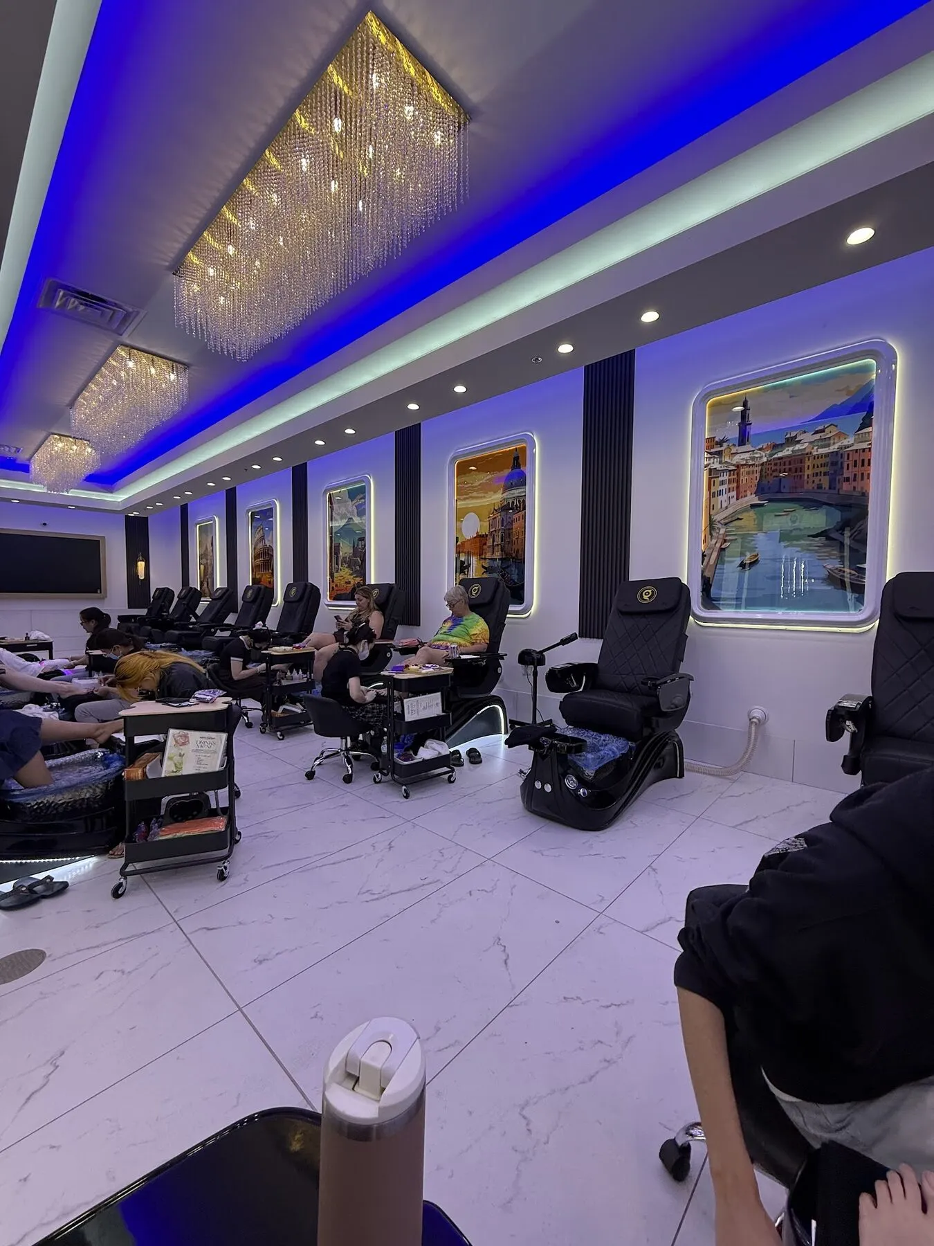 Ambient blue-lit pedicure hall lined with framed travel artwork