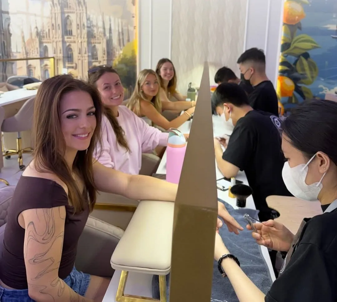 Happy guests and the Gloss team along the manicure bar beside the hand-painted Italian mural at Gloss Nail Bar Niles