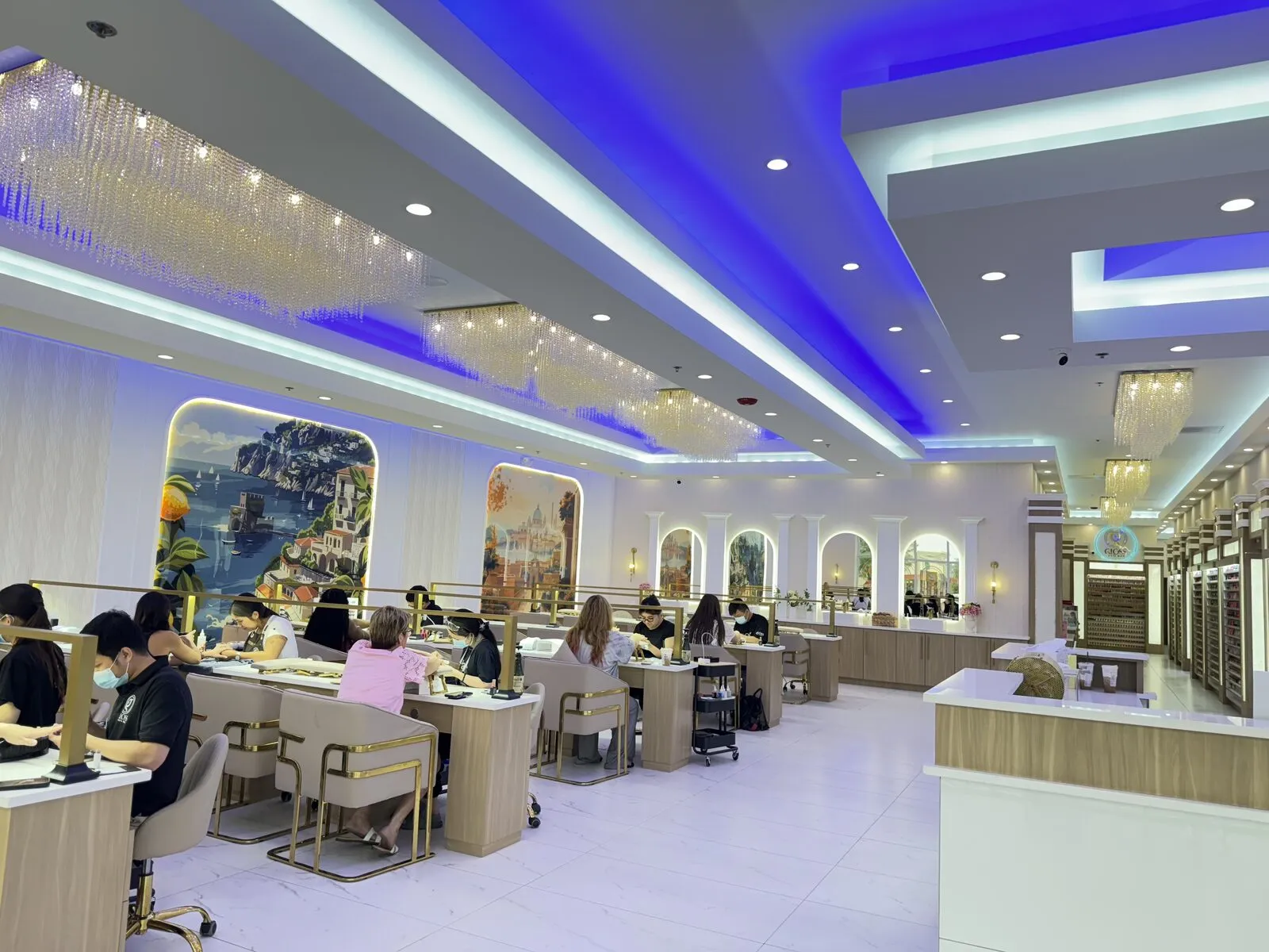 Grand manicure hall with cascading chandeliers, coastal murals and gold-and-cream stations busy with guests