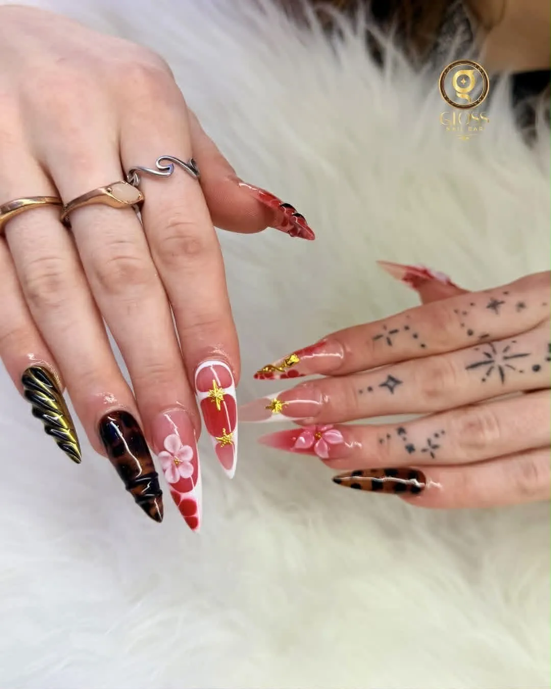 Red-and-white nails with gold star accents, tortoiseshell chrome and a 3D flower